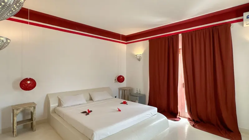 A bedroom with red curtains and white linen